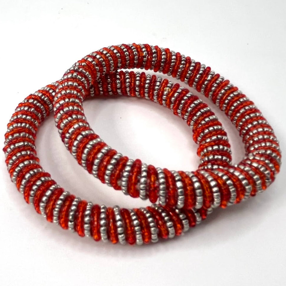 Two beaded stretch bracelets with alternating red and silver metallic beads, arranged in a loop on a plain white background.