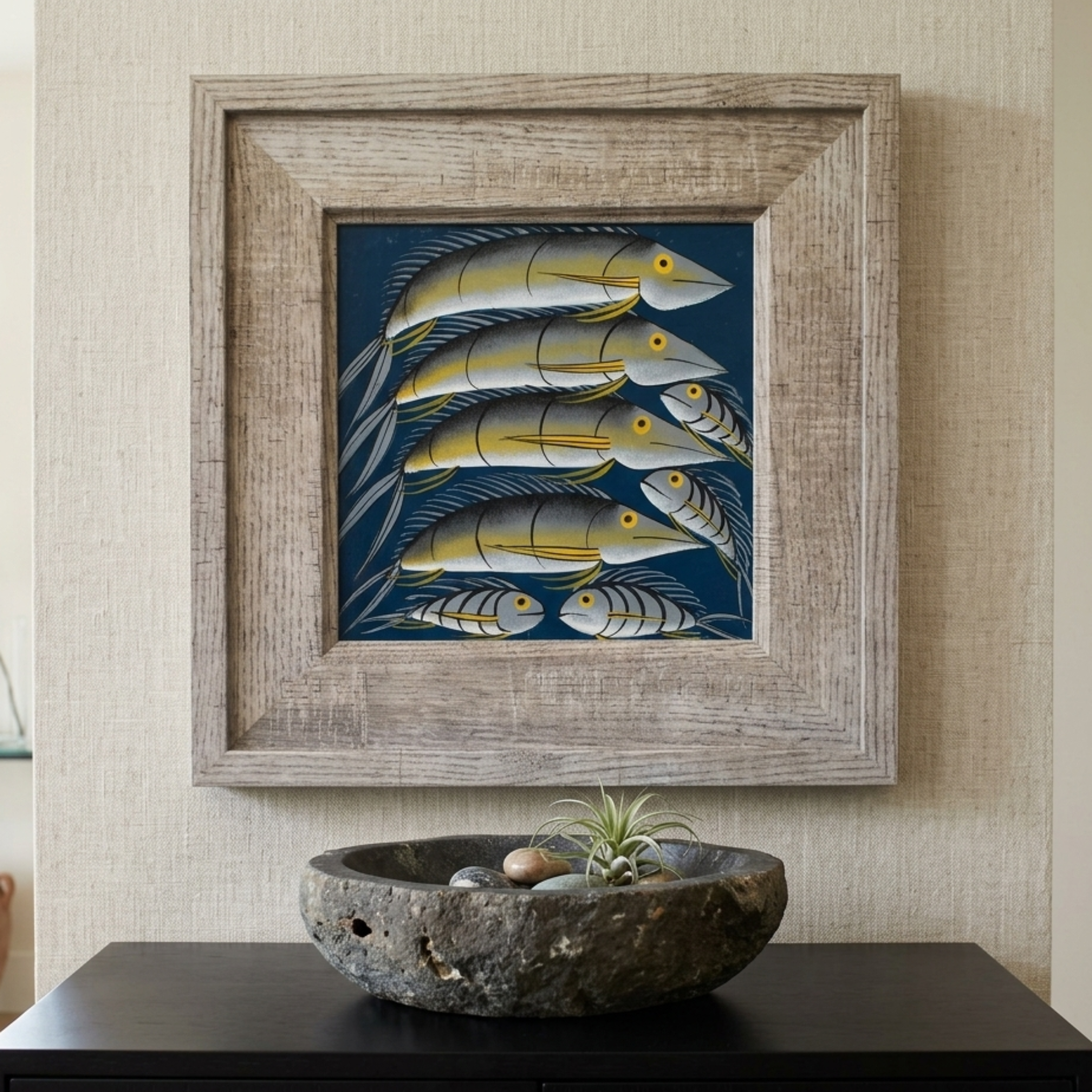 Framed artwork of fish on a wall above a dark surface with a decorative bowl.