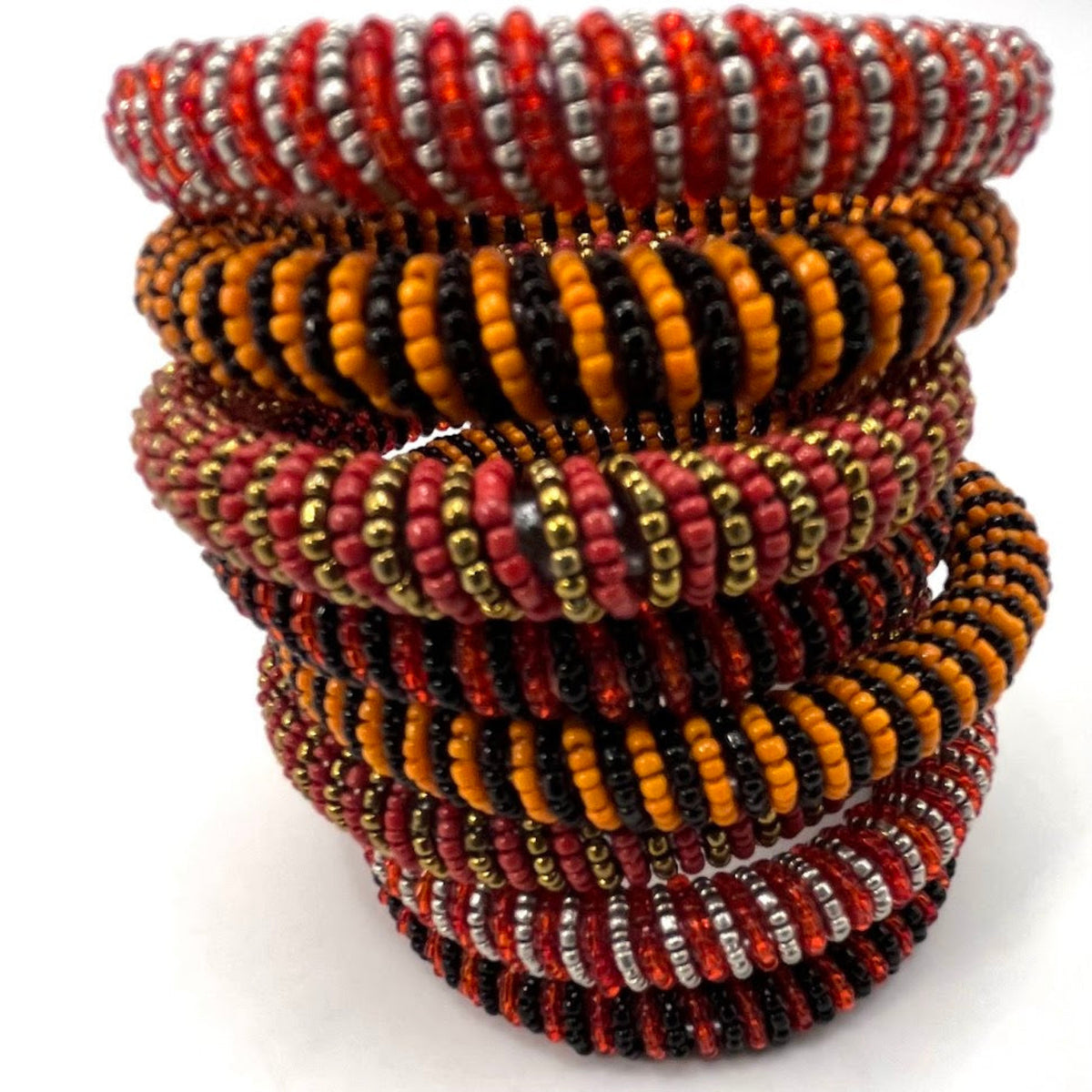 A stack of handmade beaded bracelets with intricate patterns of red, orange, black, silver, and gold seed beads, photographed on a clean white background.