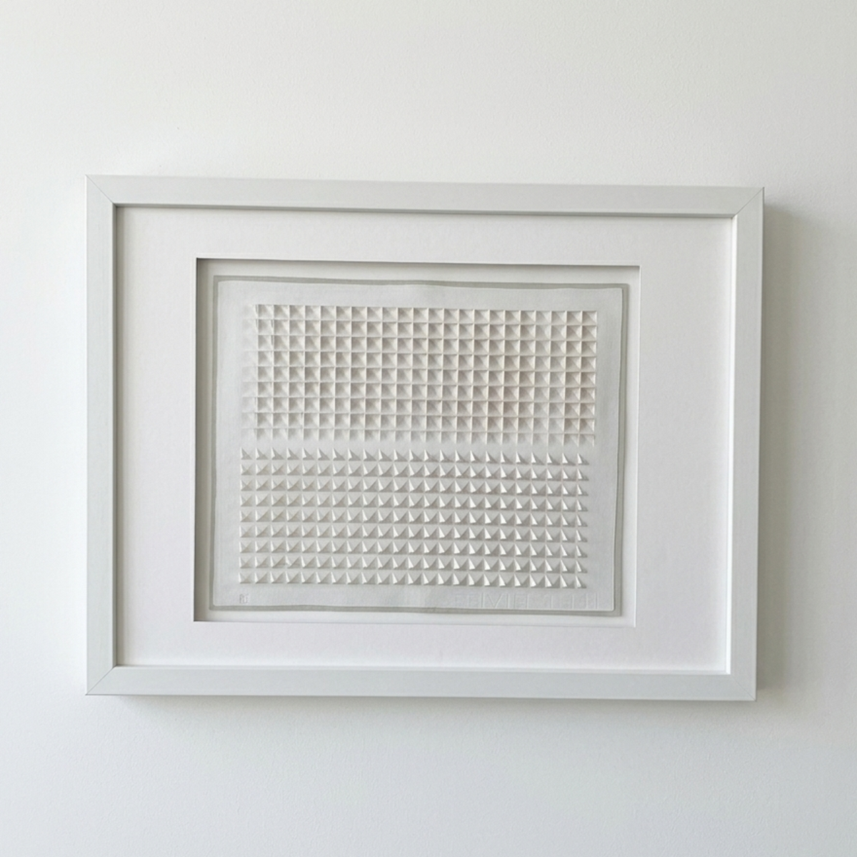 Framed artwork with geometric cut pattern on a white wall